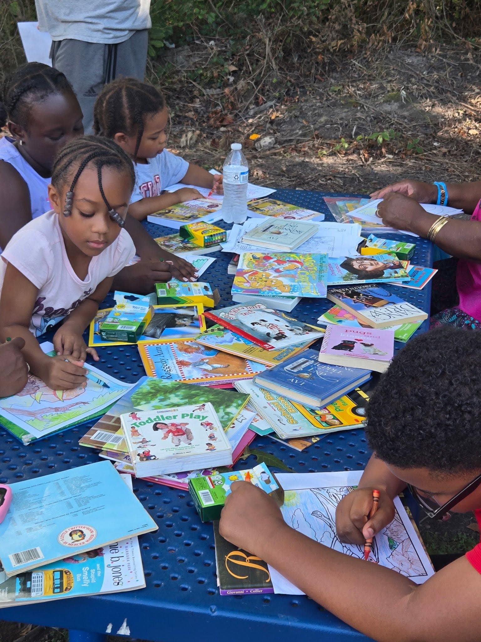 Children reading books at an outdoor table during a P2P Read-In